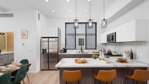 A modern kitchen with a large island, stainless steel appliances, and pendant lighting.