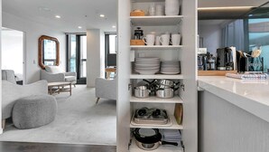 A modern kitchen with white cabinetry, a built-in oven, and a coffee station.
