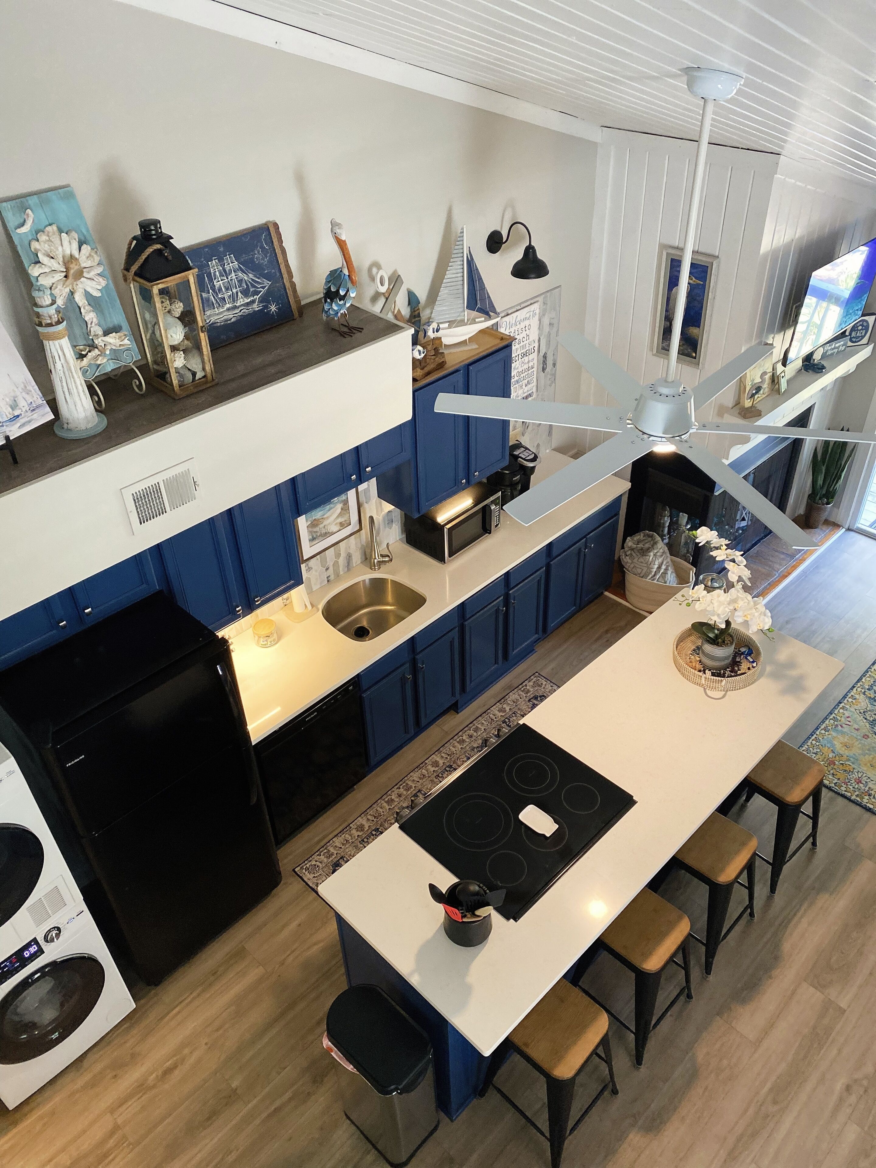 Una cocina moderna con armarios azules, una isla central, un microondas y un lavabo.