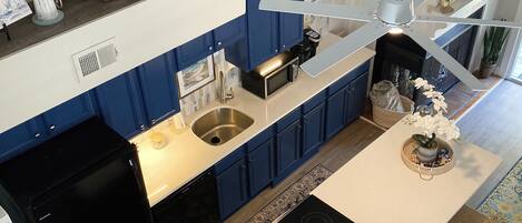 Una cocina moderna con armarios azules, una isla central, un microondas y un lavabo.