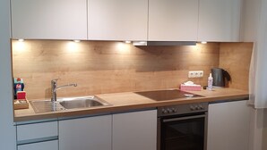 A modern kitchen with white cabinets, a wooden countertop, a stainless steel sink, and an oven. - Ferienwohnung 54qm mit Sep. Schlafzimmer und Terrasse (Prien am Chiemsee)