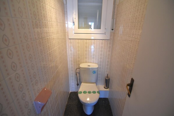 Un baño con azulejos decorativos, un inodoro, un bidé y una ventana.