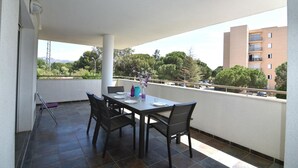 Un balcon avec une table à manger pour quatre personnes, des chaises et une petite lampe de table.