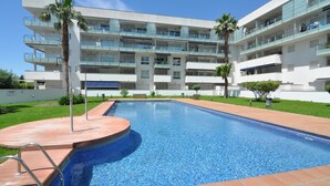 Un hôtel moderne doté d’une piscine, de nombreux balcons et de palmiers.