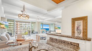 A modern kitchen with granite countertops, a stainless steel sink, and a dining area with a glass table and chairs.