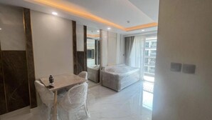 A hotel room with a bed, a small table, and a chair, all covered in plastic. - Stunning 1 bed apartment in Lamung District (Thailand)