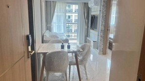 A hotel room with a glass table, two chairs, a bed, and a balcony with a view of the building. - Stunning 1 bed apartment in Lamung District (Thailand)