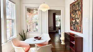 Un interior moderno con comedor, un ventanal grande, un ventilador de techo y una obra de arte abstracta.