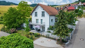 A two-story house with a balcony, surrounded by greenery and a paved driveway. - Holiday Apartment 'Hohfelsenblick' with Terrace, Balcony and Wi-Fi (Seebach)