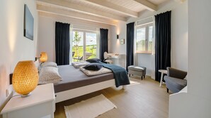 A bedroom with a bed, bedside table, lamp, and a view of the outdoors. - Holiday Home "Waldwasserhaus Leisel" with Mountain View, Private Terrace & Wi-Fi (Leisel)