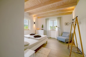 A bedroom with a bed, bedside table, lamp, and a window with curtains. - Holiday Home "Waldwasserhaus Leisel" with Mountain View, Private Terrace & Wi-Fi (Leisel)