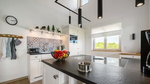 A modern kitchen with a black countertop, white cabinets, a clock, and a window with a view. - Holiday Home "Waldwasserhaus Leisel" with Mountain View, Private Terrace & Wi-Fi (Leisel)