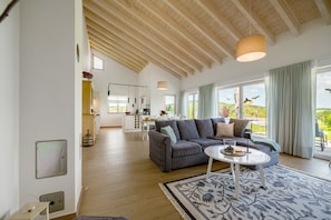 A spacious living area with a sofa, coffee table, and large windows. - Holiday Home "Waldwasserhaus Leisel" with Mountain View, Private Terrace & Wi-Fi (Leisel)