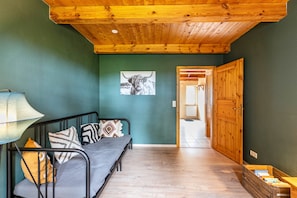 A room with a bed, a lamp, a wooden door, and a framed picture on the wall.