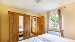 Een slaapkamer met een groot bed, een houten garderobe en een raam met gordijnen.