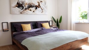 Una cama grande con estructura de madera, cabecera y varios almohadones.