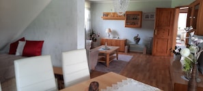 Une pièce comprenant un lit, une table à manger, un coin cuisine et une porte en bois.