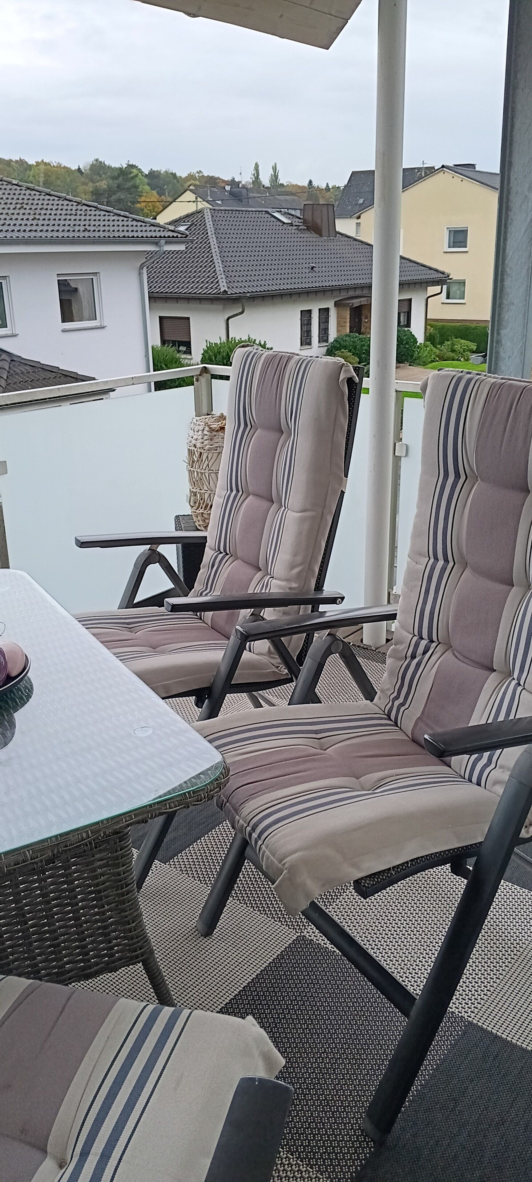 En terrasse med to polstrede stole, et lille bord og en fletstol.