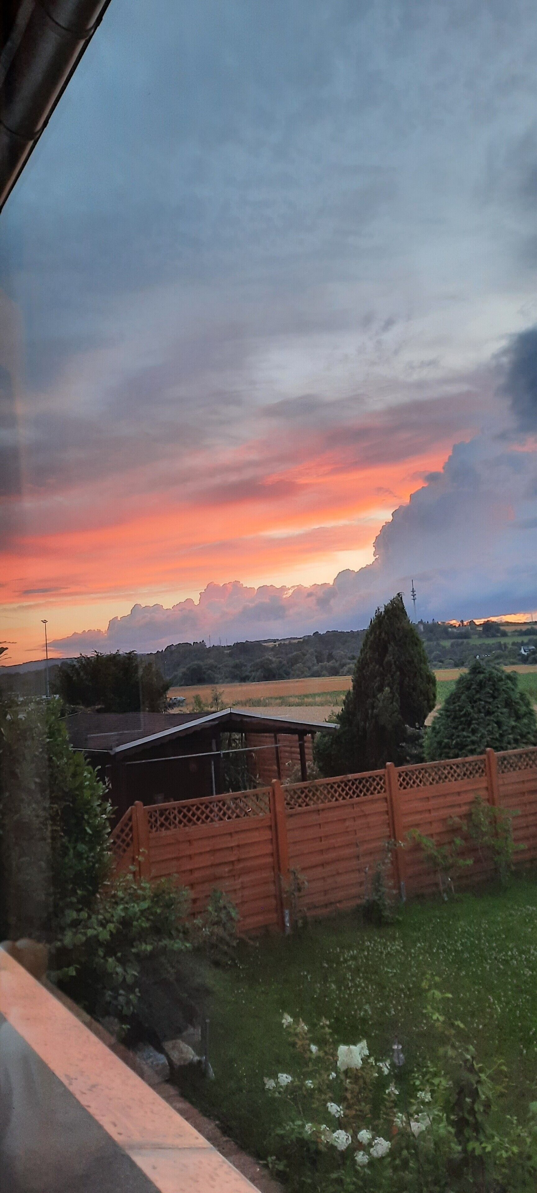 Ländliche Landschaft mit Sonnenuntergang, offenen Feldern und einem Holzzaun.