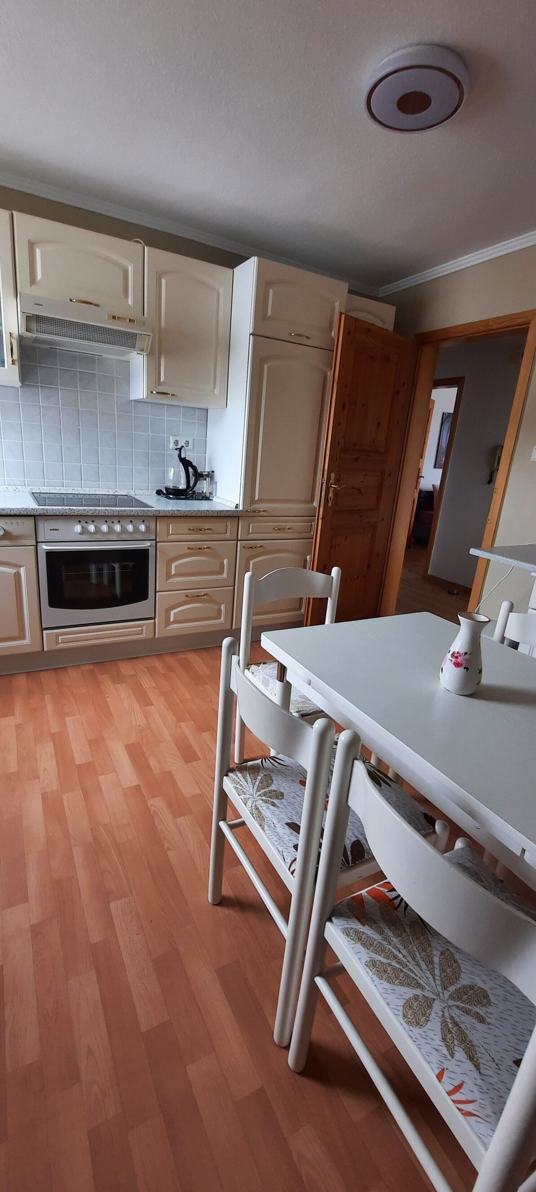 Una cocina con armarios de madera, horno empotrado y una mesa de comedor con sillas.