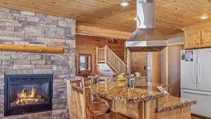 Una cocina con chimenea de piedra, encimera de madera y campana extractora de acero inoxidable.