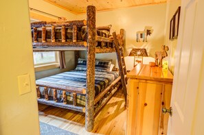 Ein Etagenbett mit Holzleiter, eine Holzkommode und ein Fenster mit Blick.