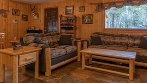 L’intérieur d’un chalet accueillant, avec un plancher en bois, deux canapés, une table basse et une bibliothèque.