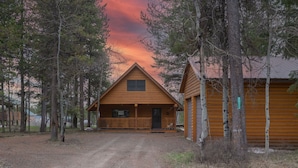 Une cabane dotée d’une véranda, entourée d’arbres, et un chemin de terre qui y mène.