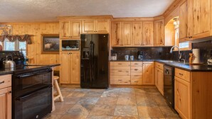Une cuisine avec des meubles de rangement en bois, un réfrigérateur noir, une cuisinière et un lave-vaisselle.