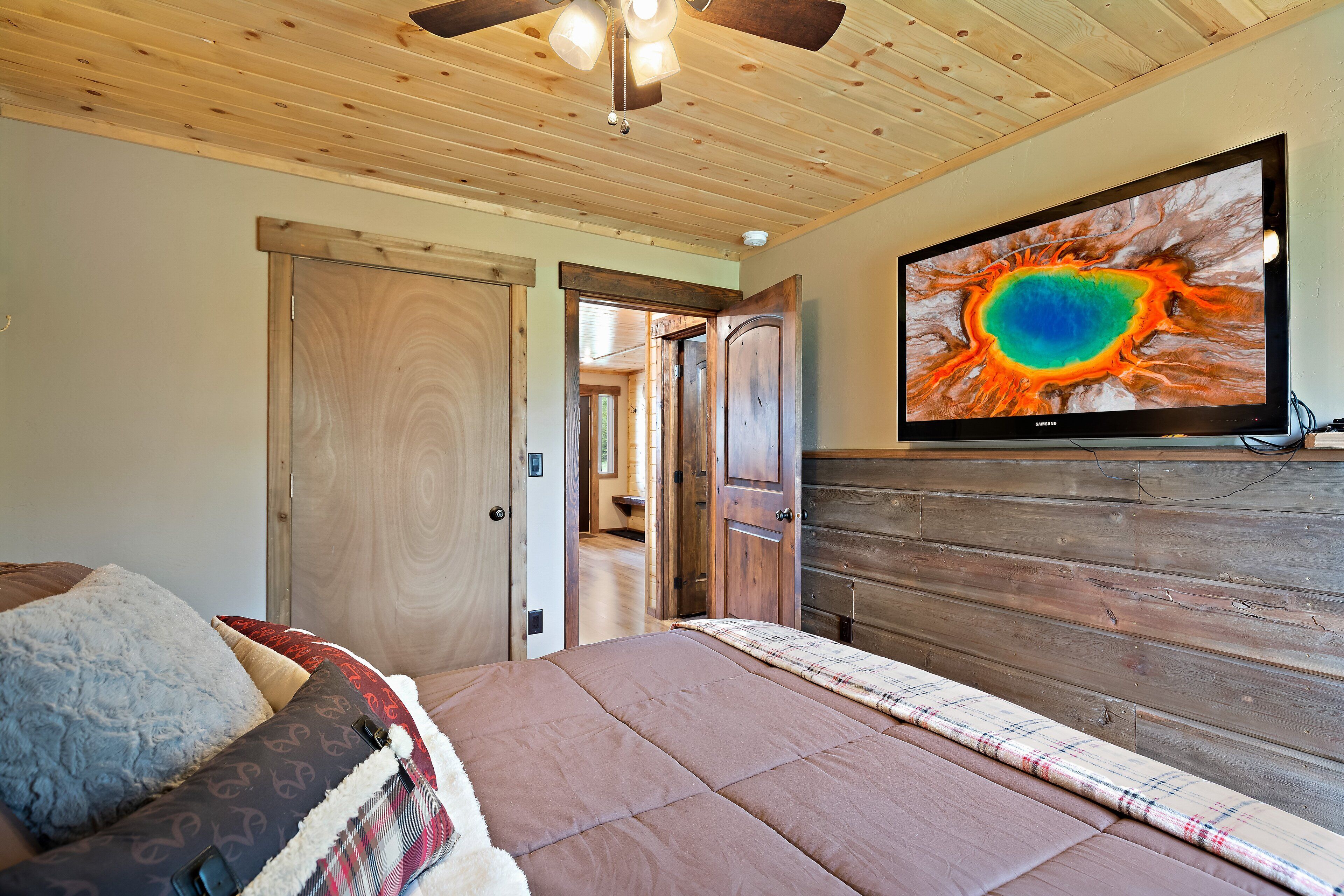 A bedroom with a bed, wooden headboard, and a television displaying a colorful image.