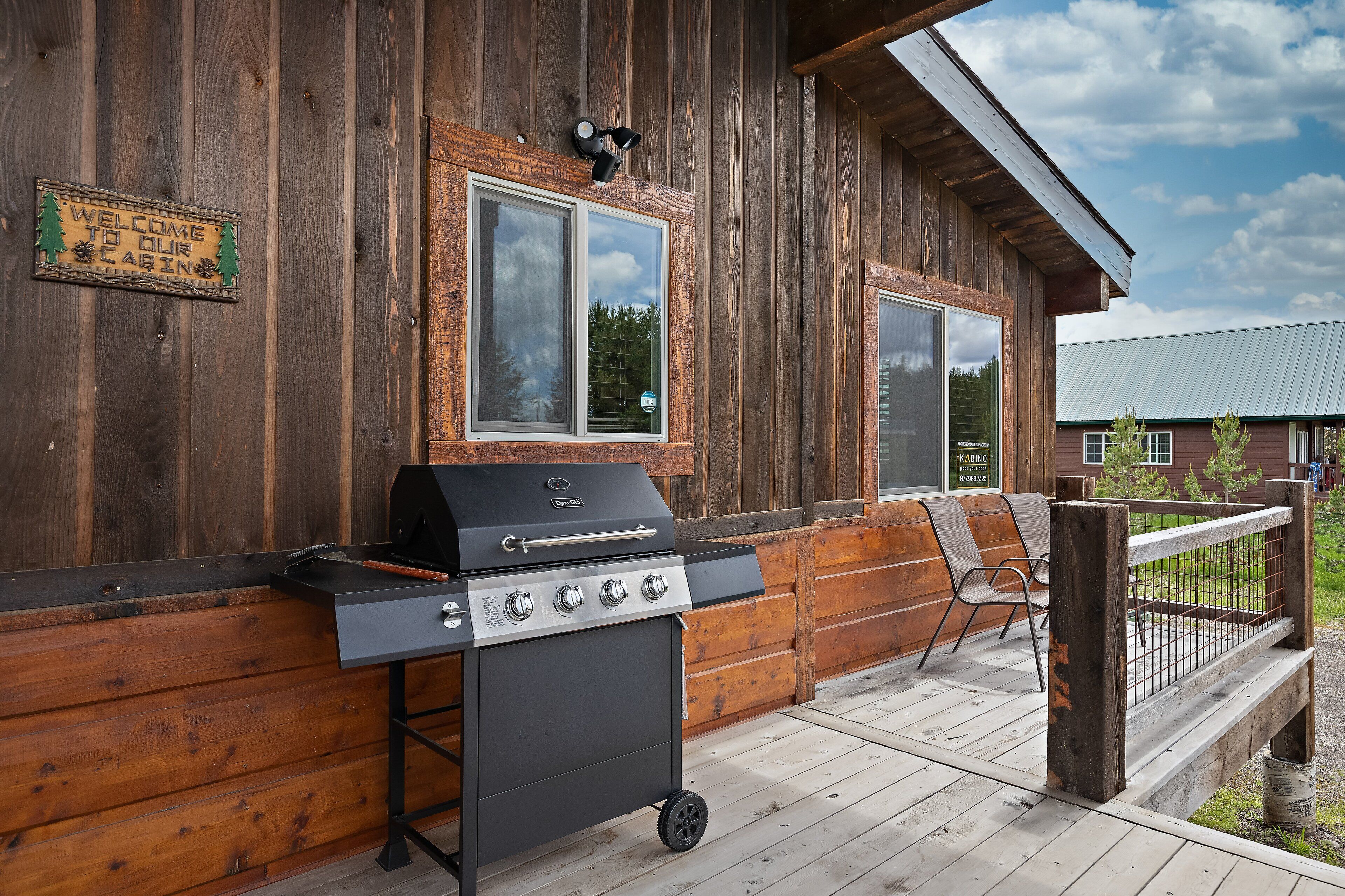 A wooden deck with a grill and a welcome sign.