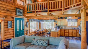 Ein Holzblockhaus-Interieur mit Wohnzimmer, Essbereich und Küche.