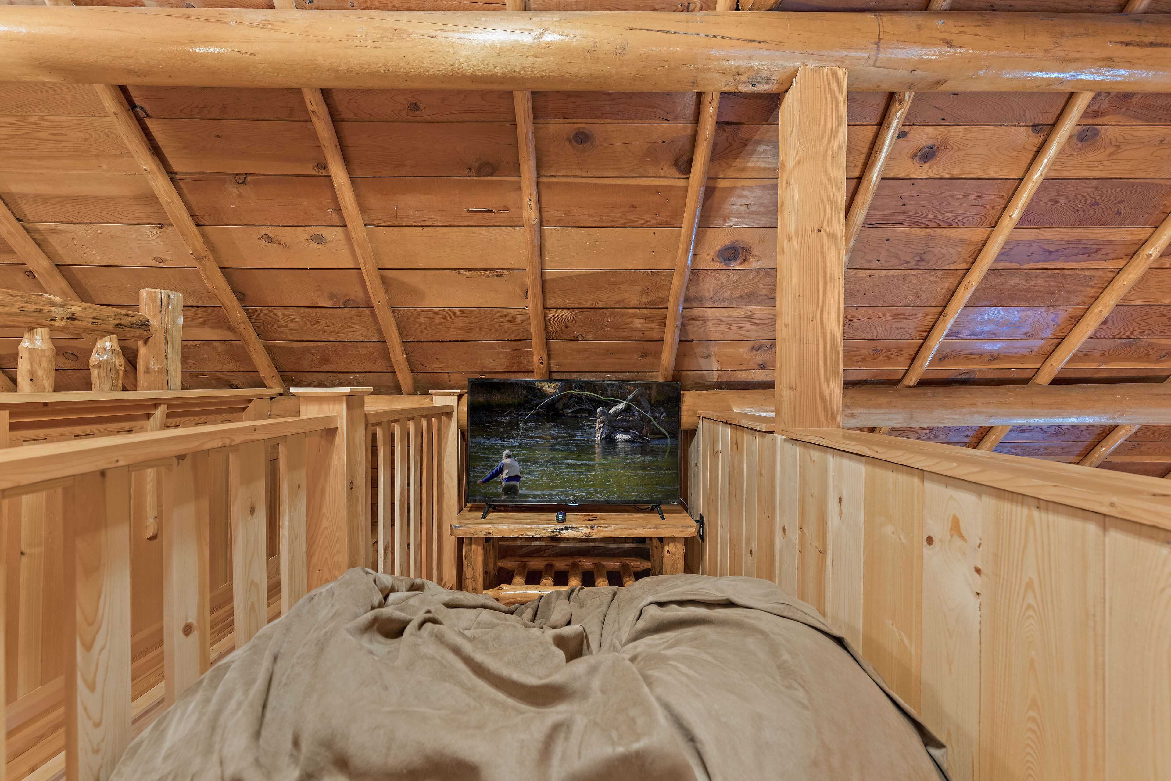 A wooden interior with a television on a stand, wooden walls, and a sloped ceiling.