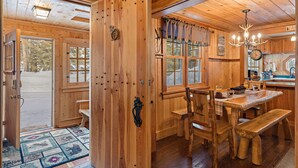 A wooden cabin interior with a dining area, wooden walls, and a large window. - Double Loop (Island Park)