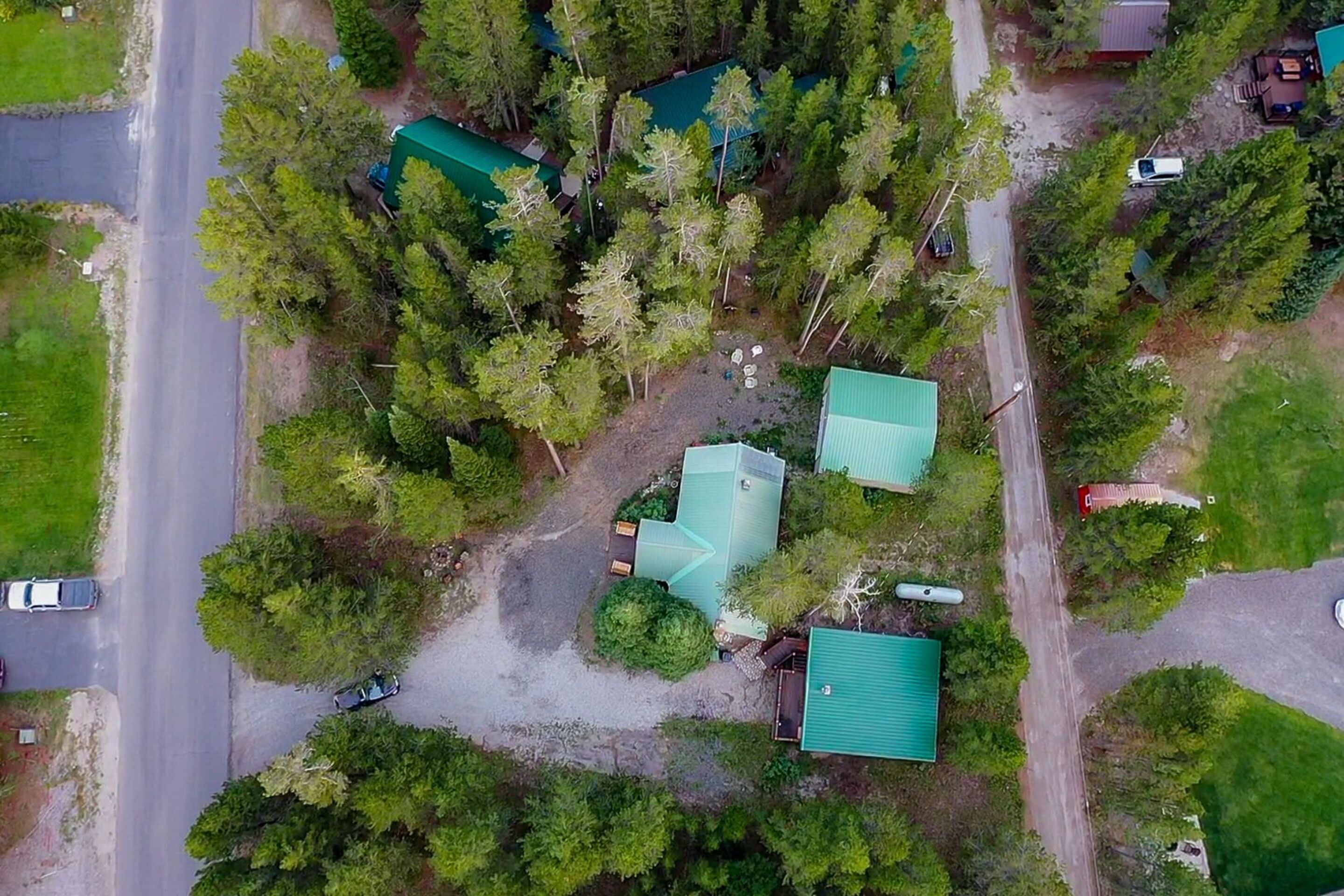 An aerial view of a residential area with multiple houses, a main road, and surrounding greenery.