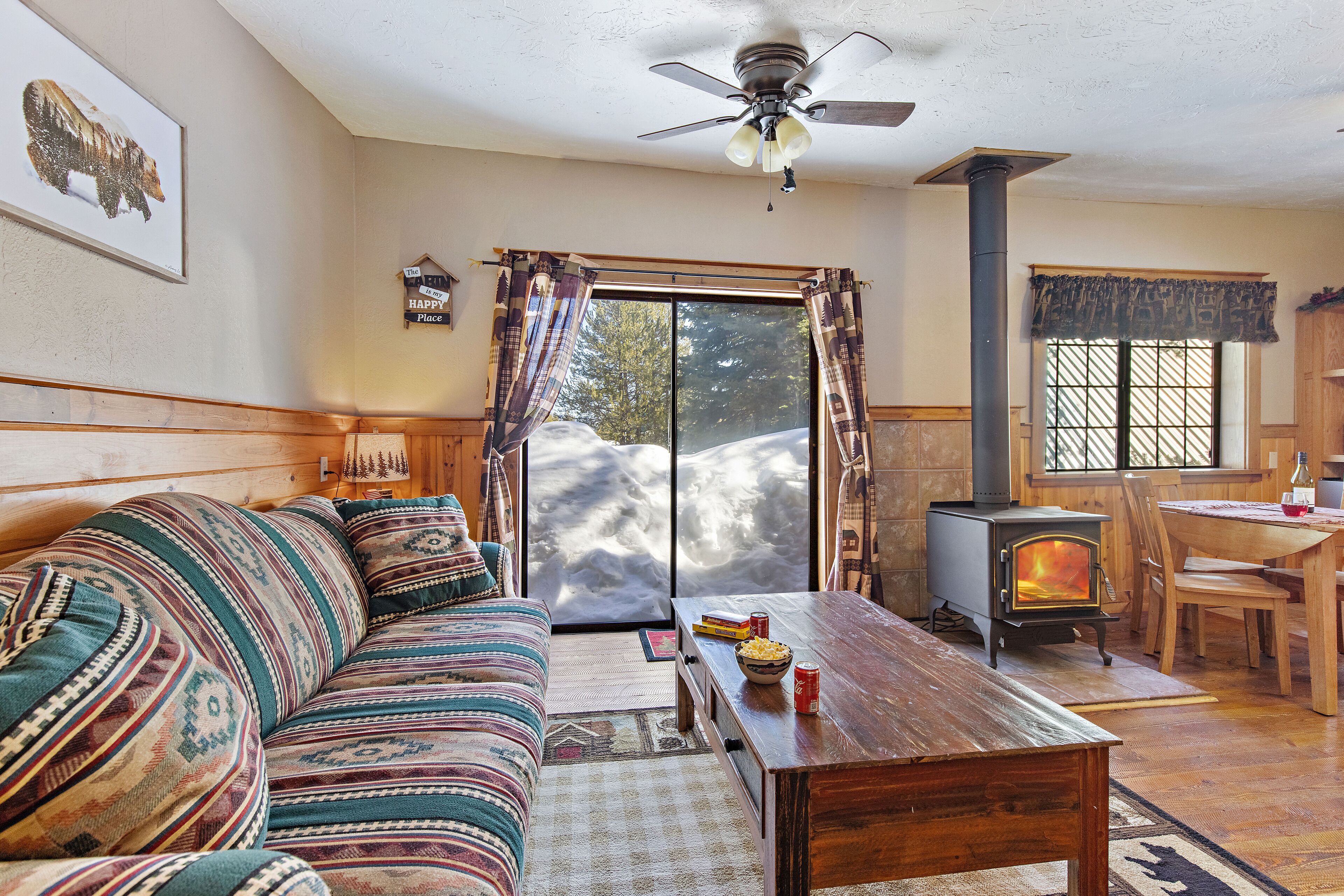 A cozy living room with a sofa, wooden coffee table, and a wood-burning stove.