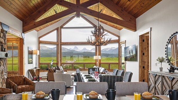Un amplio comedor con vistas a montañas, vigas de madera en el techo y un candelabro.