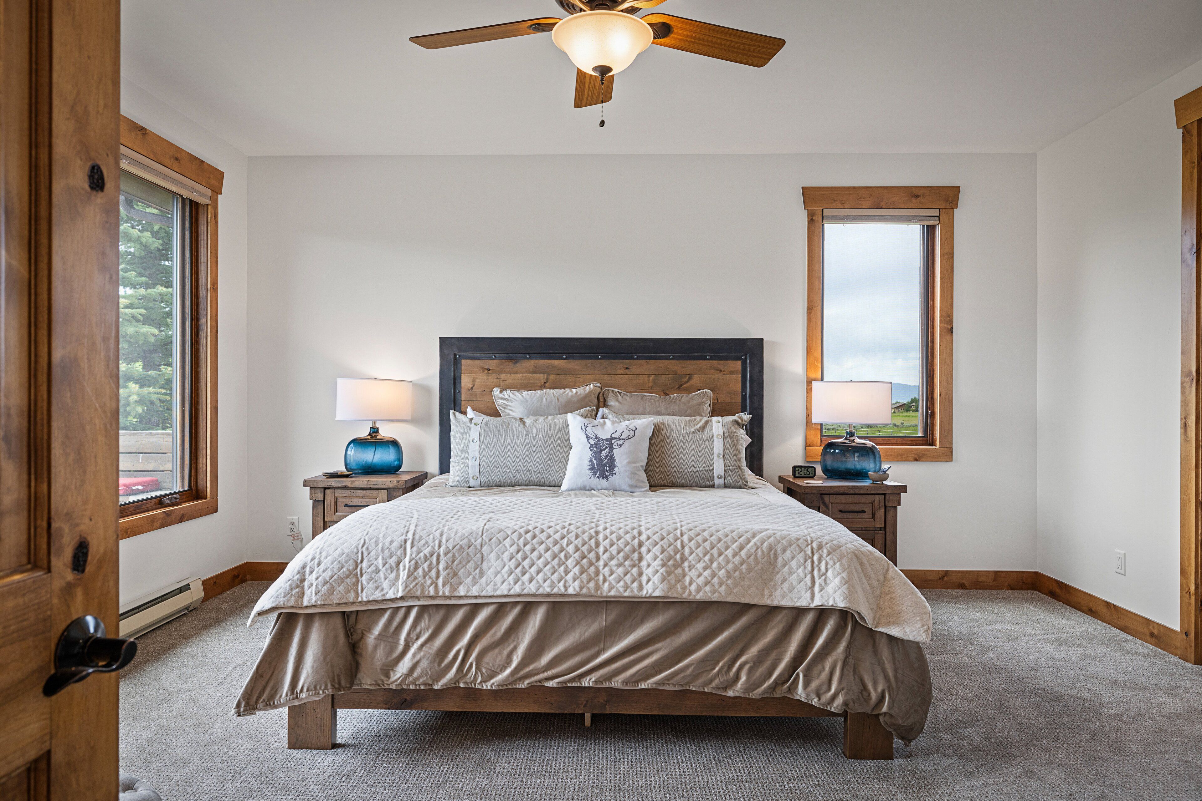 A bedroom with a large bed, wooden headboard, two bedside tables with lamps, and a ceiling fan.