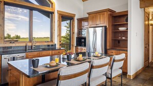 Una cocina moderna con armarios de madera, una isla grande con asientos y vistas al exterior.