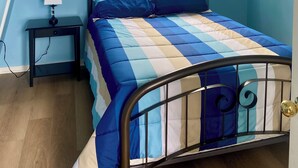 A bedroom with a bed, a nightstand, a mirror, a window, and a blue wardrobe.
