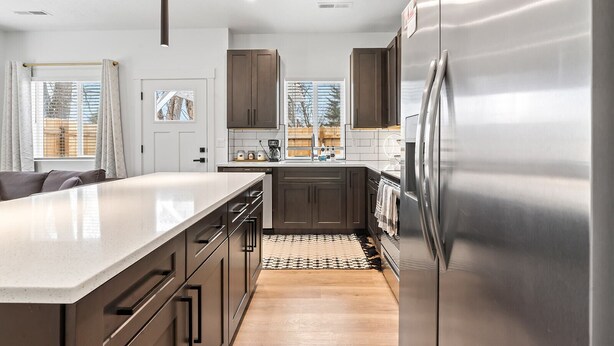 A modern kitchen with stainless steel appliances, a large island, and dark wooden cabinets. - The Stargazer in Boise (Garden City)