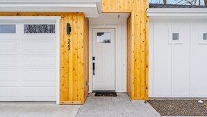 A modern house with a white garage door, a wooden front door, and a small porch area. - The Stargazer in Boise (Garden City)