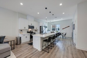 A modern kitchen with white cabinetry, stainless steel appliances, and a central island with bar stools. - Luxury 4 Bed / 3.5 Bath Townhome near Sports/CHOC/Disneyland/Chapman/Beach (Anaheim)