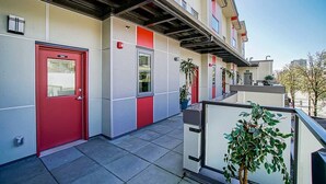 A building exterior with a red door, a fire alarm, and a potted plant. - Delux River View Home 2beds (New Westminster)