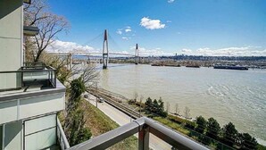 A modern building with a balcony overlooking a river and a bridge. - Delux River View Home 2beds (New Westminster)