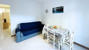 Un soggiorno accogliente con divano, tavolo da pranzo e sedie, e un quadro appeso al muro.