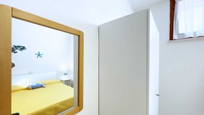 Una camera da letto con un letto, un comodino, una decorazione a stella marina e una finestra con tende.