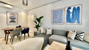 A modern living room with a grey sofa, a wooden coffee table, a dining table with chairs, and artwork on the walls. - A12 Stylish and Modern 2bds in La Marsa (La Marsa)