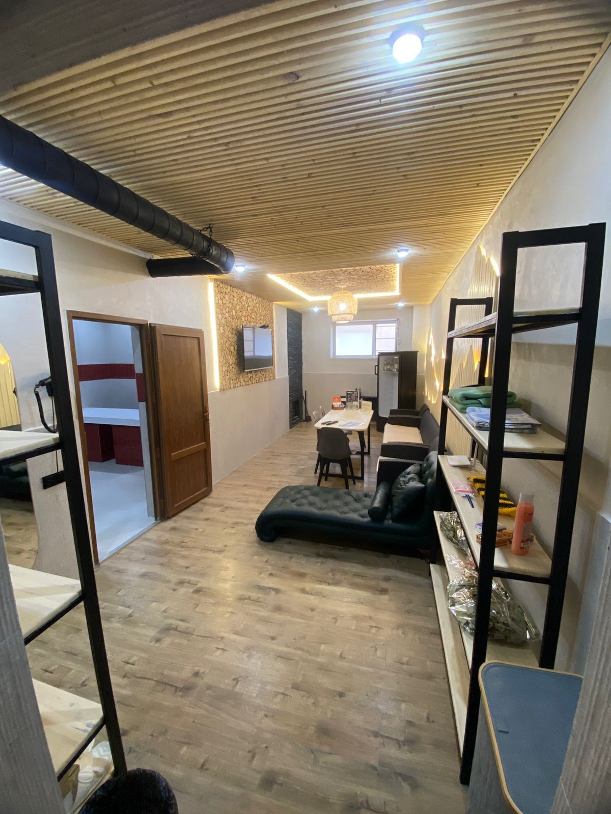 Une pièce de style loft avec un plafond haut, des conduits apparents, un coin repas, un canapé et des lits superposés.