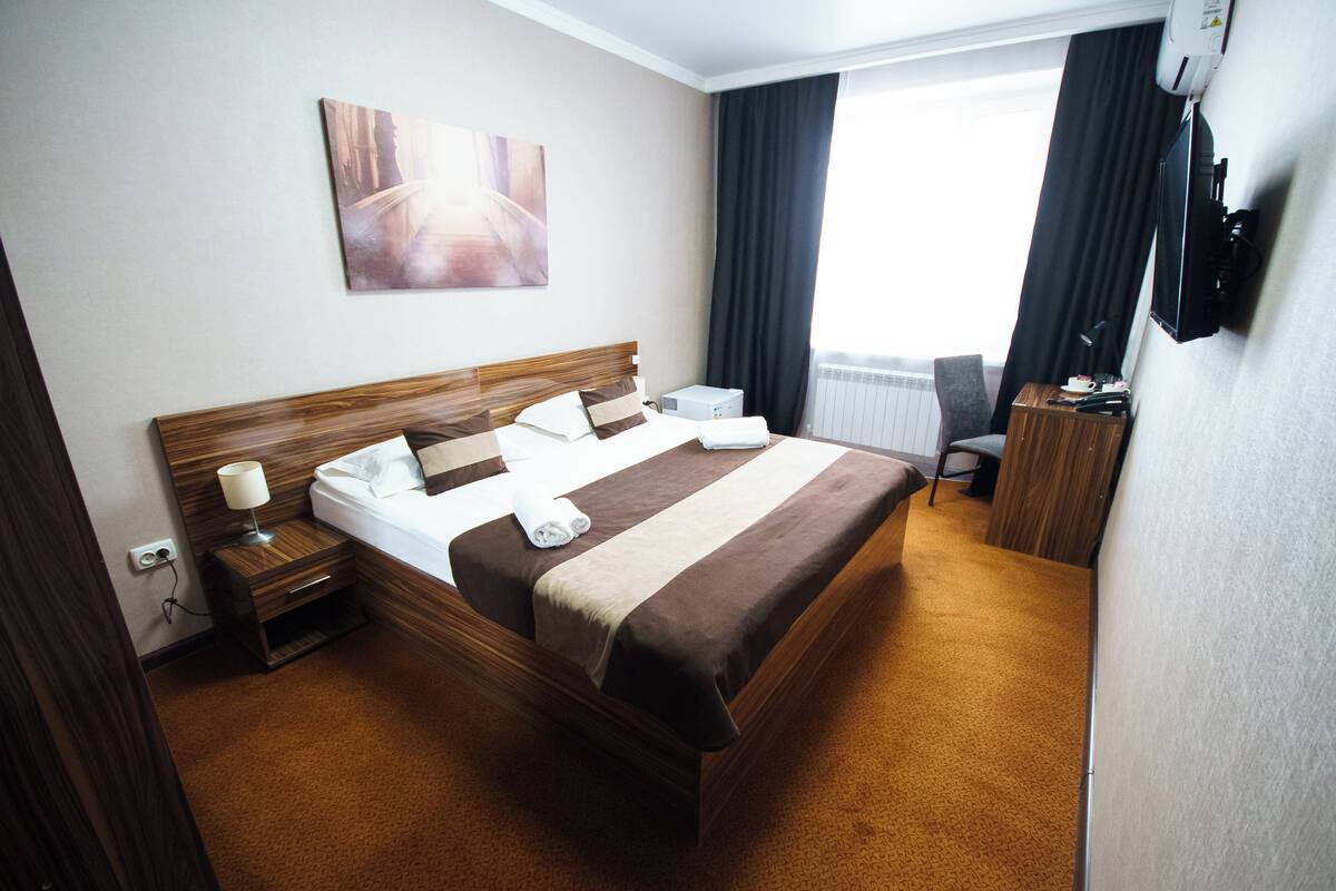 Une chambre d’hôtel avec un grand lit, des tables de chevet, une télévision et une vue sur l’extérieur.